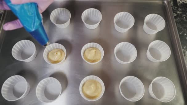Руки шеф-повара с кондитерскими пакетами наполняют тесто для выпечки кексов в бумажных стаканах . — стоковое видео