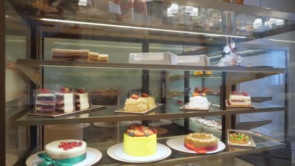 Vitrina de panadería con pasteles y pasteles en estantes de vidrio . — Vídeos de Stock