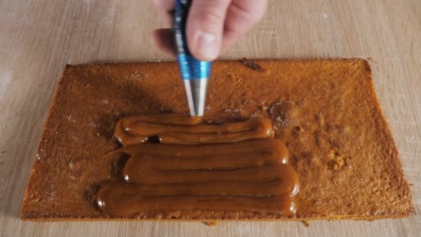 Banketbakker chef zet de karamel vullen van gebak zak op de spons cake. — Stockvideo