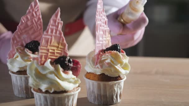 Baker está rociando cupcakes decorados con purpurina dorada . — Vídeos de Stock