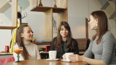 Bir kafede üç kız konuşuyor ve içecekler içiyor