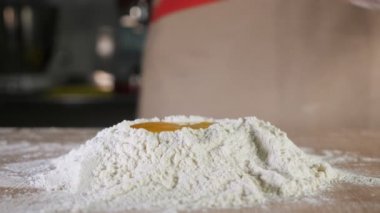 Baker is making a dough on the table. Hands close-up.