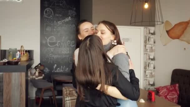 Τρεις γυναίκες φίλους είναι το αγκάλιασμα μαζί χαιρετισμό. Φιλική συνάντηση σε καφετέρια. — Αρχείο Βίντεο