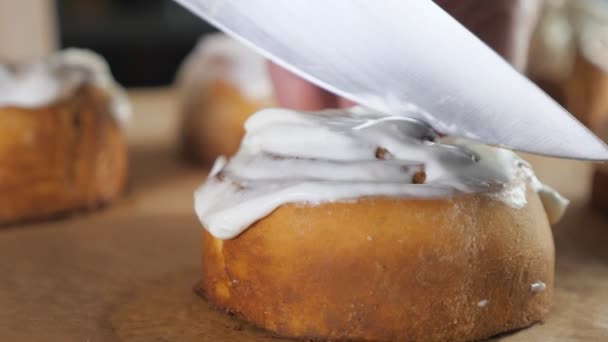 Pastelero está cortando rollo de canela con crema por la mitad . — Vídeos de Stock