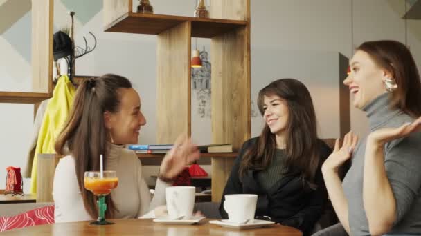 Três namoradas em um café estão conversando e bebendo suas bebidas — Vídeo de Stock