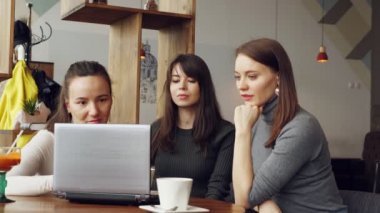 Successful women team in coworking center: reading a message with good news in laptop an then giving a five to each other.