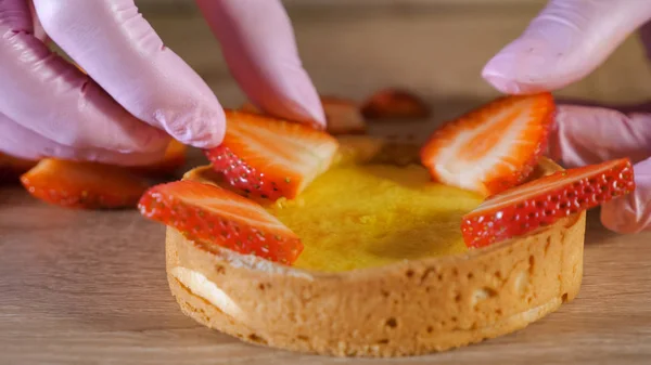Konditor macht Mini-Kuchen mit Sahne und Erdbeerscheiben. — Stockfoto