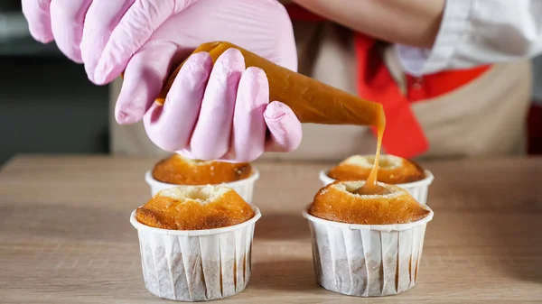 Konditor füllt Muffins in Pappbecher Karamellfüllung mit Teigtasche — Stockfoto