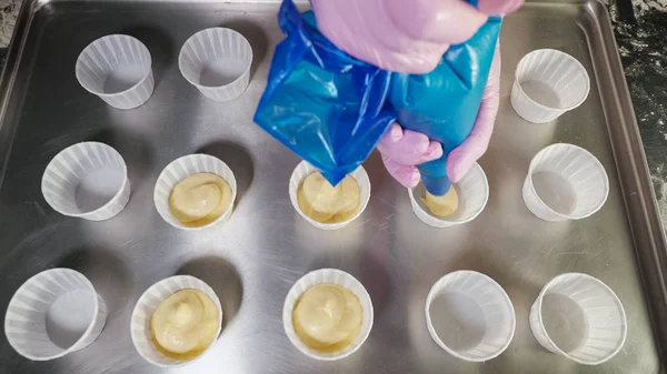Руки шеф-повара с кондитерскими пакетами наполняют тесто для выпечки кексов в бумажных стаканах . — стоковое фото