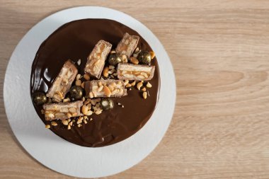 Masanın üzerinde sır, fıstık ve çikolata parçaları ile çikolatalı kek.