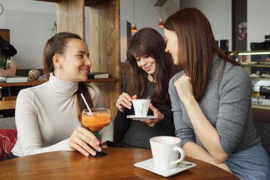 Üç kadın kız bir kafede konuşmak ve onların içecekler içme