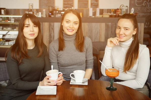 Drei Freundinnen in einem Café unterhalten sich und trinken ihre Getränke — Stockfoto