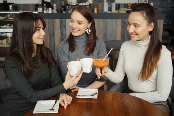 Tre flickvänner träffas i caféet. Dricka drycker och talar varandra. — Stockfoto