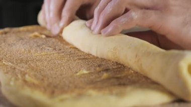 Baker Şef masada bir rulo içine tarçın, şeker ve tereyağı ile hamur rulo.