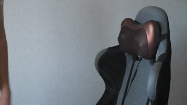 yorgun adam elektrikli masaj yastığı ile koltukta oturuyor