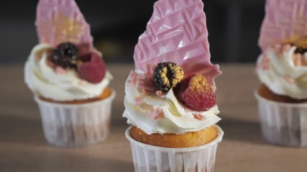 Cupcakes con crema, gofres y bayas frescas en vasos de papel sobre la mesa . — Vídeos de Stock