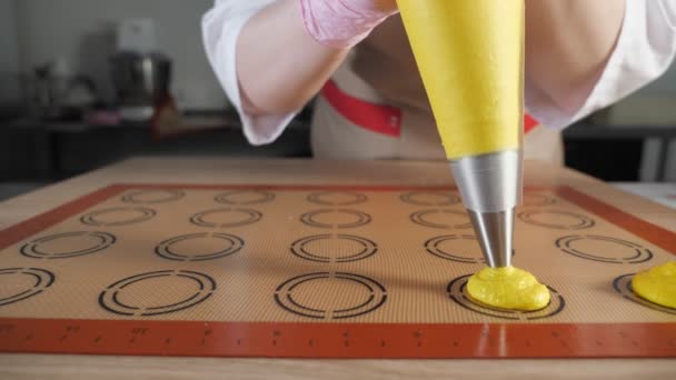 Banketbakker is koken macaroons. Gieten deeg op stencil siliconen mat. — Stockvideo