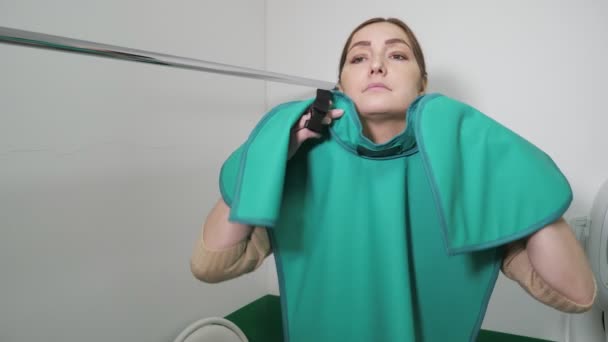 Young woman is putting on x-ray protection apron preparing for tooth x-ray. — 비디오