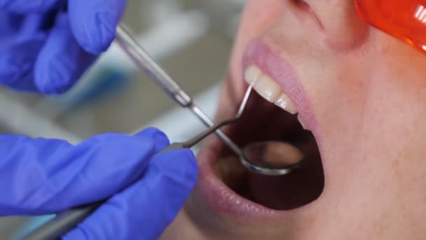 Tandläkare som behandlar tänder till kvinnlig patient på klinik. — Stockvideo