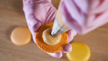 Pasta şefi şekerleme torbası kullanarak krem limon macaroons dolduruyor.