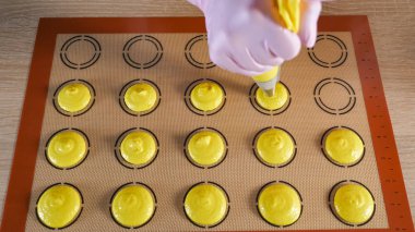 Pasta şefi macaroons pişiriyor. Şablon silikon mat hamur dökme.