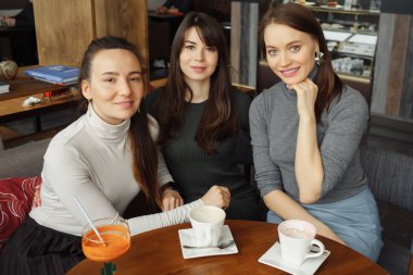 Bir kafede içecek ile üç kadın kız konuşuyor