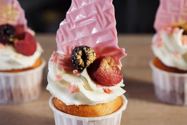 Cupcakes con crema, gofres y bayas frescas en vasos de papel sobre la mesa . —  Fotos de Stock