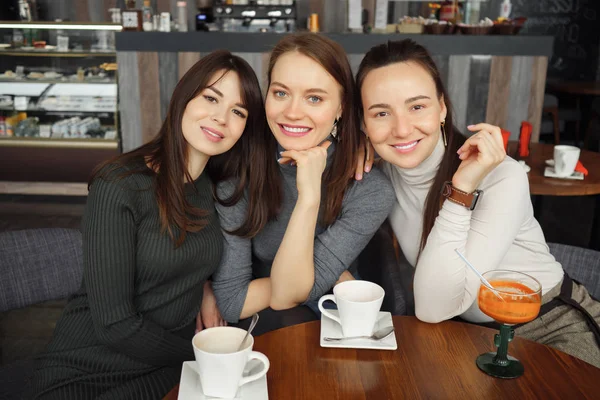 Tre kvinnor flickvänner i café pratar och dricka deras drycker — Stockfoto