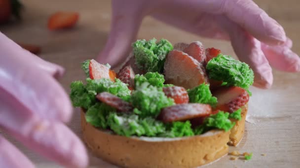 Konditor i gummi handskar visar fyllning av styckning i halv jordgubbs mini kaka. — Stockvideo