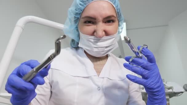 Dentista mujer médico está sosteniendo instrumentos dentales fórceps y aguja en las manos y mirando a la cámara . — Vídeo de stock