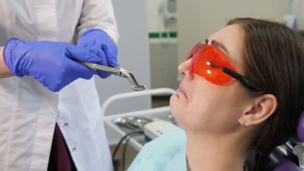 Young woman afraid to remove a tooth sitting in dental chair while the doctor stands next to the patient, holding forceps in hands. — 图库视频影像