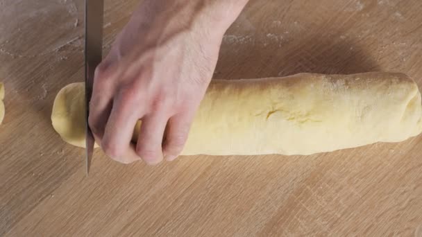 Bäckermeister schneidet Rolle mit Zimt, Zucker und Butter auf Portionen, um Zimtröllchen zu backen. — Stockvideo