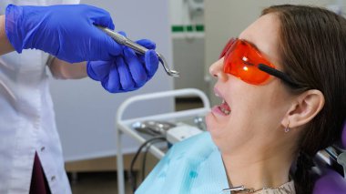 Doktor elinde penslerle hastanın yanında dururken dişini diş sandalyesine oturtmaktan korkan genç bir kadın..