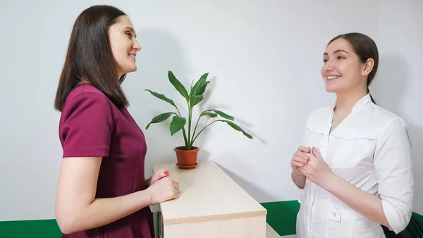 Дружня медсестра на прийомі розмовляє з пацієнткою молодою жінкою, вид збоку . — стокове фото