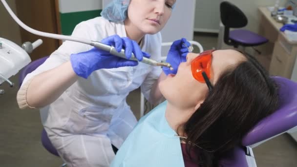 Niña en gafas protectoras en examen preventivo en silla dental en la clínica dentista. Concepto de cuidado dental . — Vídeos de Stock