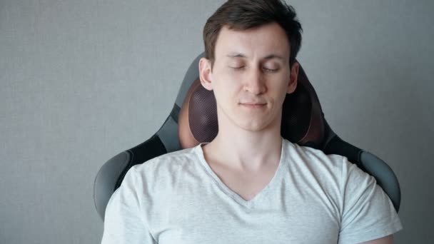 Młody mężczyzna siedzi na fotelu z elektryczną poduszką do masażu — Wideo stockowe