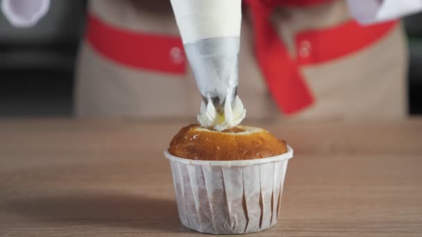 El chef de pastelería decora magdalenas en tazas de papel crema blanca con bolsa de pastelería . — Vídeos de Stock