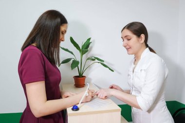 Genç bayan hasta klinikte ödevlerini yazıyor. Resepsiyonda dost canlısı bir hemşire var..