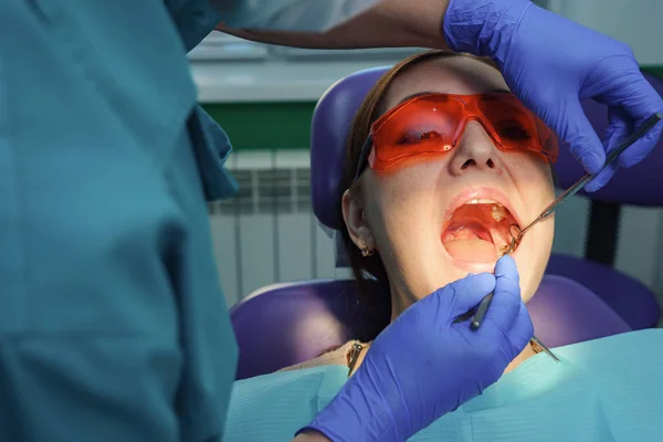 Tandarts behandeling tanden aan vrouw patiënt in kliniek. — Stockfoto