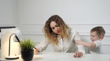 Küçük çocuk, işyerinde telefon ararken annesini işe çağırıyor. Çalışan anne.