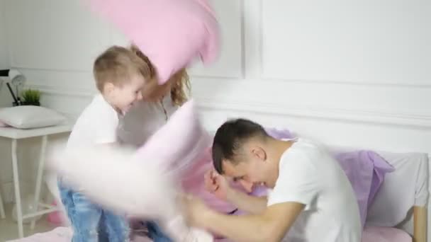 Jeune famille : maman papa et petit fils s'amusent à se battre sur le lit . — Video