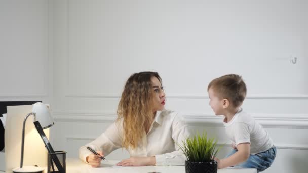 Young woman secretary with her little son in the workplace in office. Working mother. — Stok video