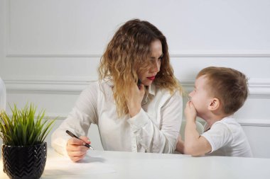Küçük çocuk, işyerinde telefon ararken annesini işe çağırıyor. Çalışan anne.