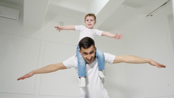 Papa speelt met zoon Sitten op zijn schouders beeltenis van een vliegtuig. — Stockvideo