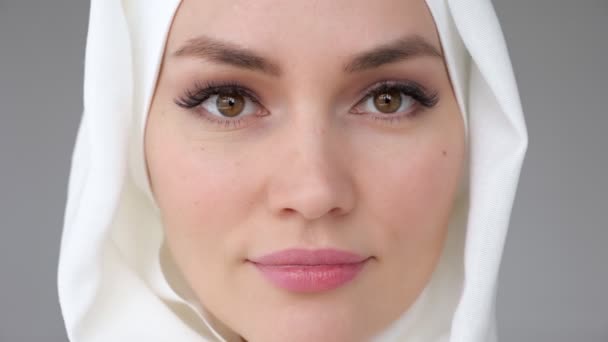 Close-up rosto de mulher muçulmana vestindo hijab está olhando para a câmera e sorrindo . — Vídeo de Stock
