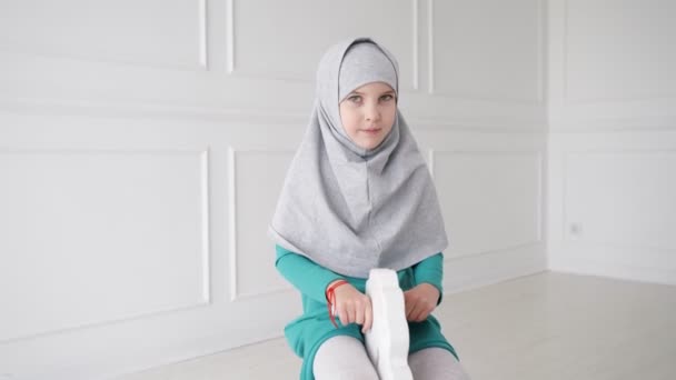 Muslim tonåring flicka i hijab och klänning spelar ridning på Toy Horse gungstol i hennes rum. — Stockvideo