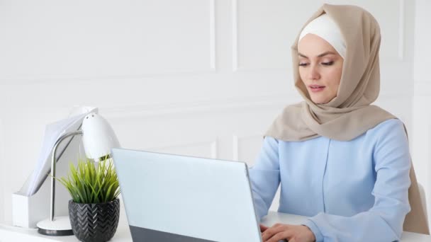 Junge Muslimin tippt im Büro auf Laptop. — Stockvideo