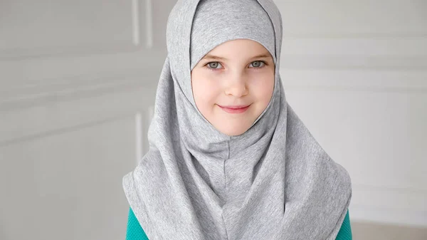 Muslimisches Mädchen im grauen Hidschab blickt in die Kamera und lacht. — Stockfoto