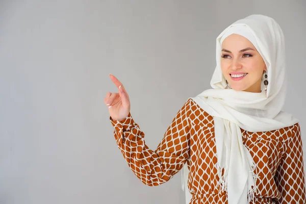 Portrait of gorgeous arab woman in headscarf pointing finger at copy space — Stock Photo, Image