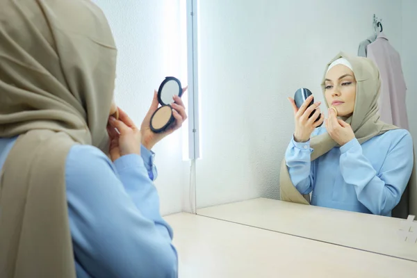 Muslim ung attraktiv kvinna i beige hijab och traditionell blå klänning Making make-up — Stockfoto
